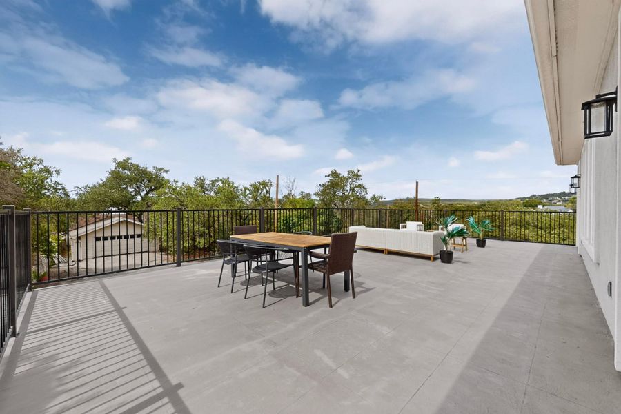 An expansive elevated terrace sits bordered by dark metal railings overlooking the surrounding treetops.