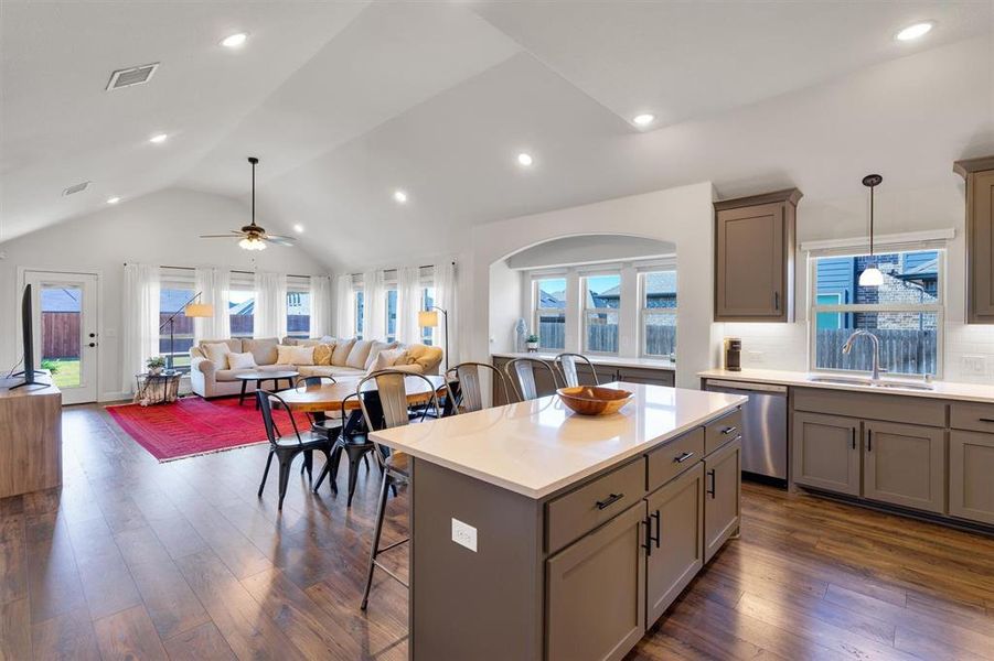 Kitchen featuring stainless steel dishwasher, ceiling fan, sink, pendant lighting, and a breakfast bar area