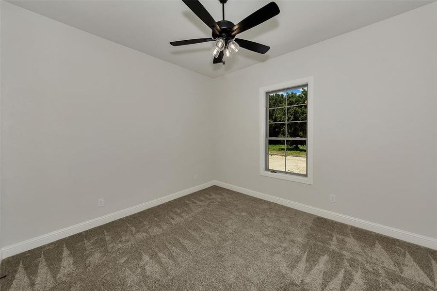 Unfurnished room featuring dark carpet and ceiling fan