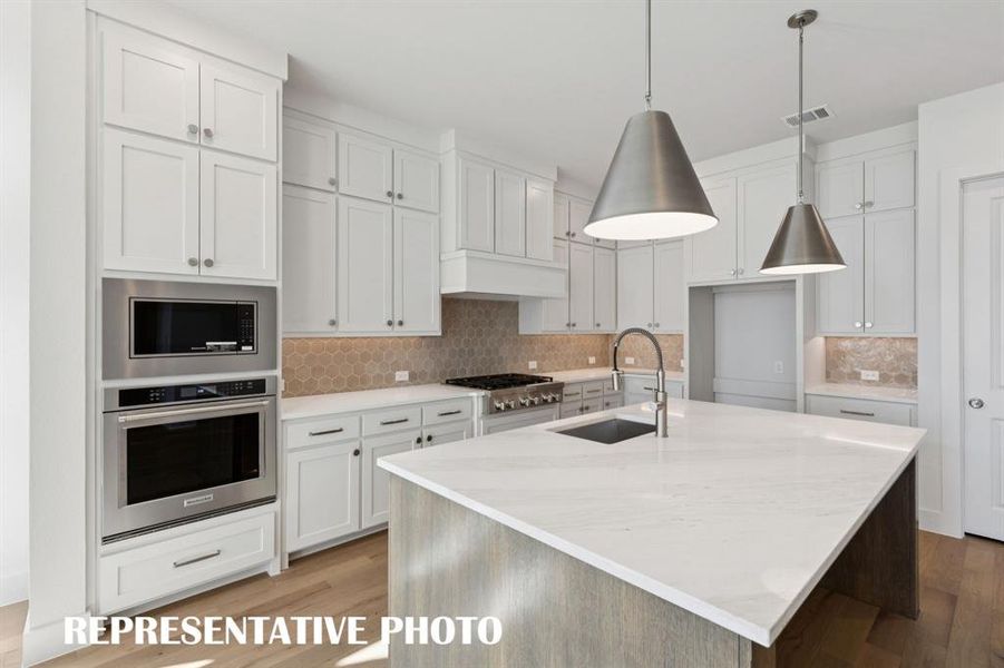 This dream kitchen features beautiful cabinets, designer backsplash, gorgeous countertops and high end stainless appliances.  What more could you ask for?  REPRESENTATIVE PHOTO