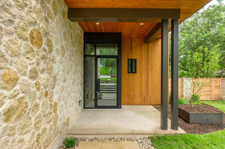 A modern entry features natural stone and wood siding, inviting residents into a contemporary living space. A modern entry features natural stone and wood siding, inviting residents into a contemporary living space.