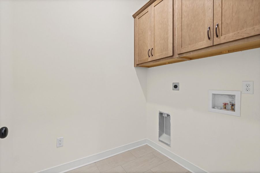 Laundry area featuring overhead cabinetry, tile flooring, and appliance hookups Laundry area featuring overhead cabinetry, tile flooring, and appliance hookups