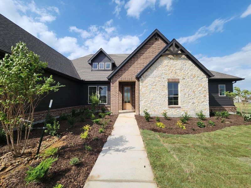Crafted residence featuring a blend of brick and stone masonry, dark horizontal siding, and a gabled roofline
