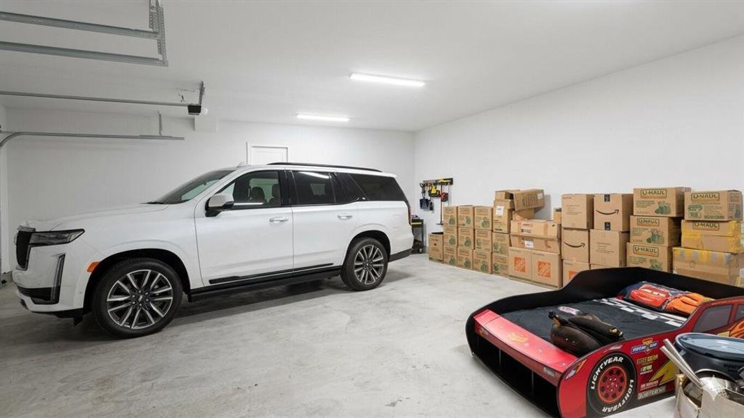 Spacious garage featuring a concrete floor, bright overhead lighting, and white painted walls