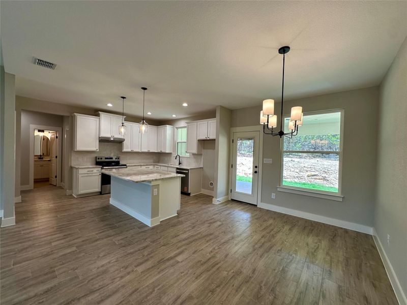 Kitchen featuring stainless steel appliances, white cabinets, dark wood-style floors, a chandelier, and recessed lighting Kitchen featuring stainless steel appliances, white cabinets, dark wood-style floors, a chandelier, and recessed lighting
