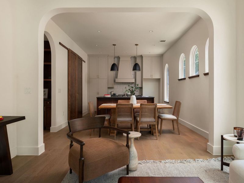 An open concept design seamlessly connects the kitchen and dining areas, illuminated by unique arched windows.