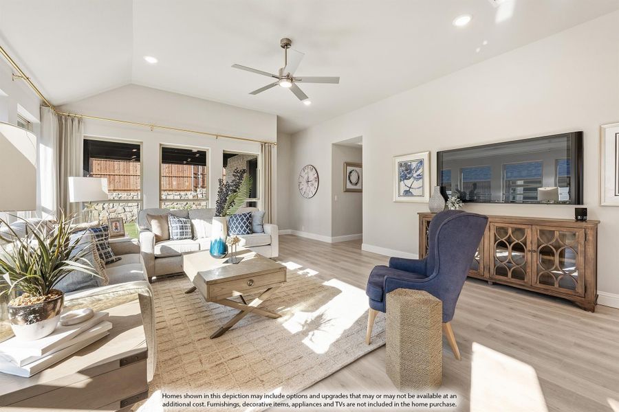 Living room with vaulted ceiling, ceiling fan, hardwood floors, and large windows overlooking backyard Living room with vaulted ceiling, ceiling fan, hardwood floors, and large windows overlooking backyard
