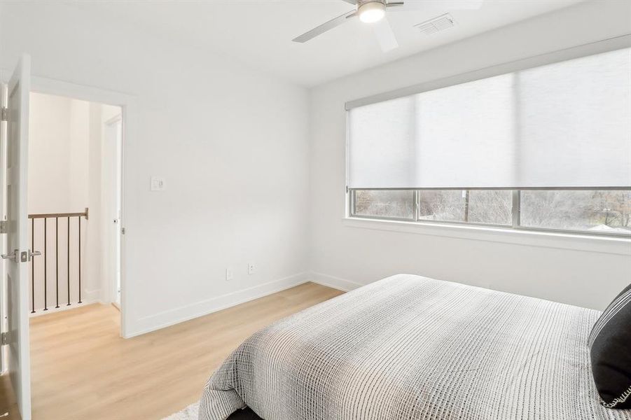 Bedroom featuring light wood finished floors, baseboards, visible vents, and a ceiling fan