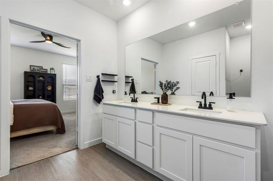 Dual vanity featuring white shaker cabinetry, light-toned countertops, and matte black fixtures Dual vanity featuring white shaker cabinetry, light-toned countertops, and matte black fixtures
