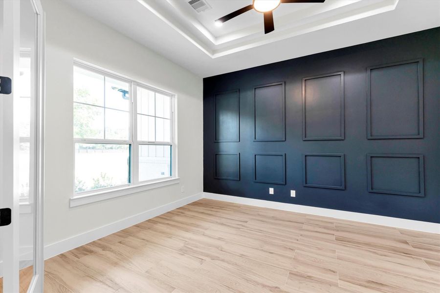 Elegant office space featuring a chic accent wall, abundant natural light, and stylish wood flooring—perfect for productivity and inspiration.