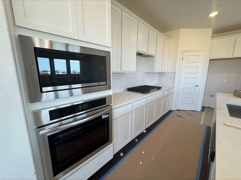 Kitchen with appliances with stainless steel finishes, white cabinetry, tasteful backsplash, and recessed lighting