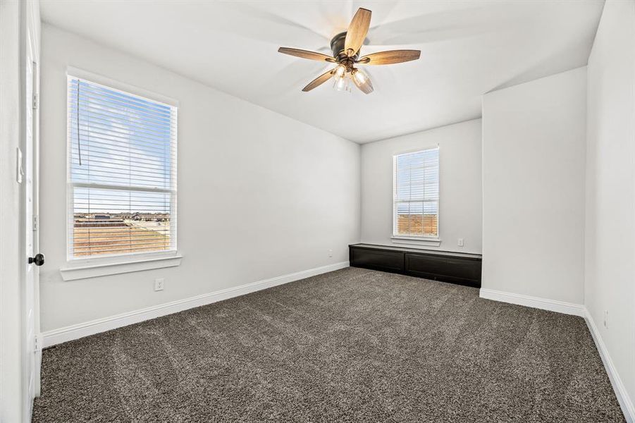 Unfurnished room with ceiling fan and dark carpet