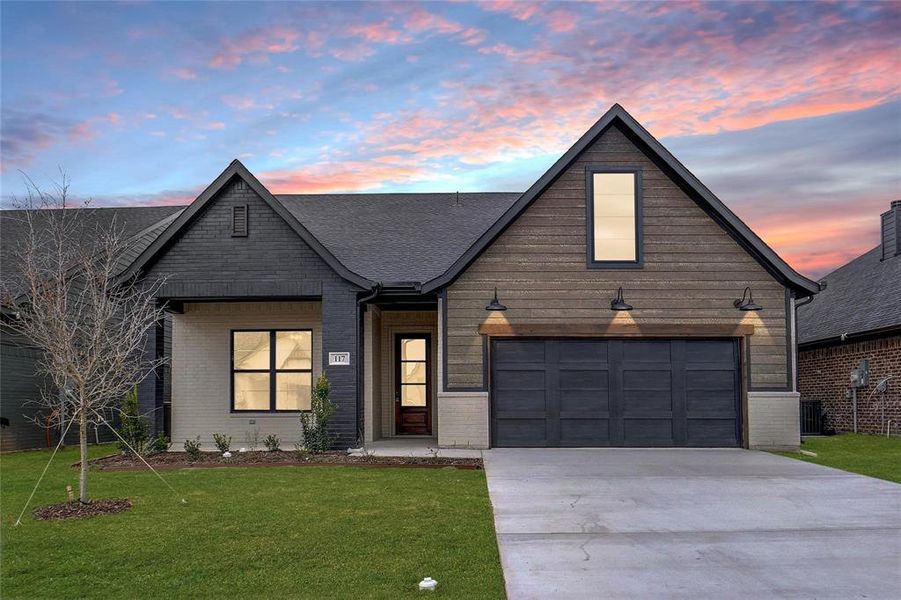 View of front of home with concrete driveway, a front yard, a garage, and brick siding