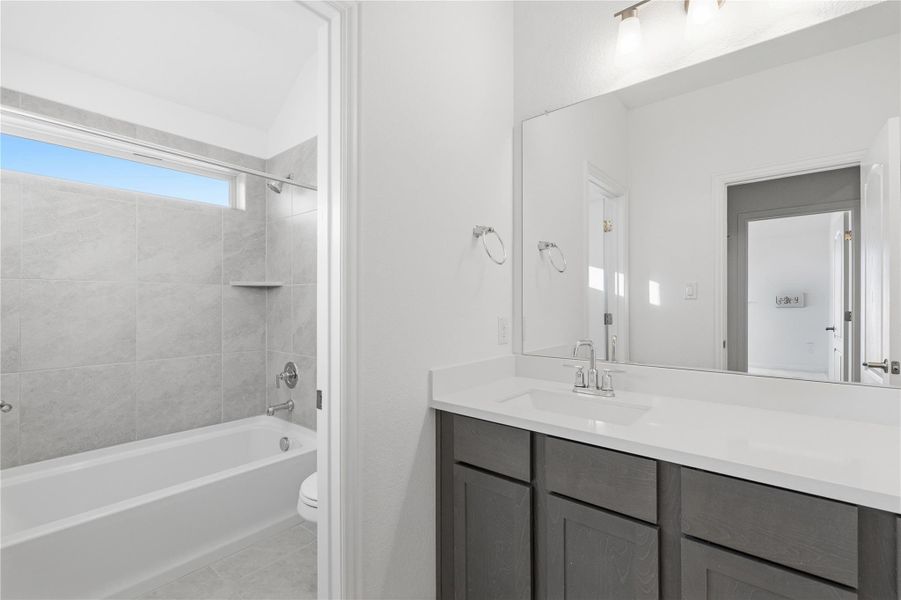 Full bath featuring bathing tub / shower combination, vanity, and light tile patterned floors