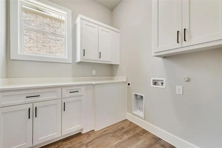 Laundry room featuring electric dryer hookup, light wood finished floors, cabinet space, hookup for a washing machine, and gas dryer hookup