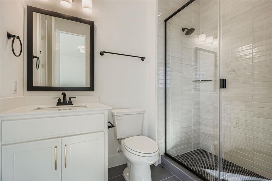 Bathroom with a stall shower, vanity, and dark tile patterned flooring