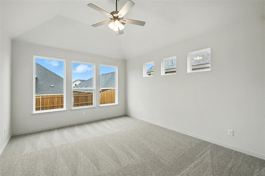 Unfurnished room featuring light colored carpet, ceiling fan, and vaulted ceiling
