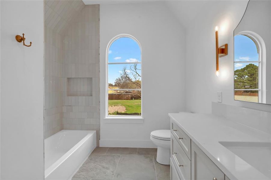 Bathroom with vanity, a bathtub, healthy amount of natural light, and light tile patterned floors