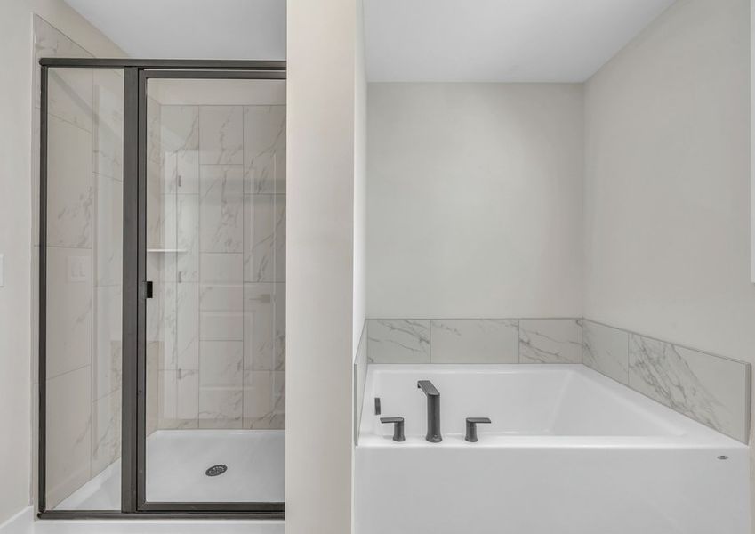 The master bathroom has a large soaking tub and glass-enclosed shower.