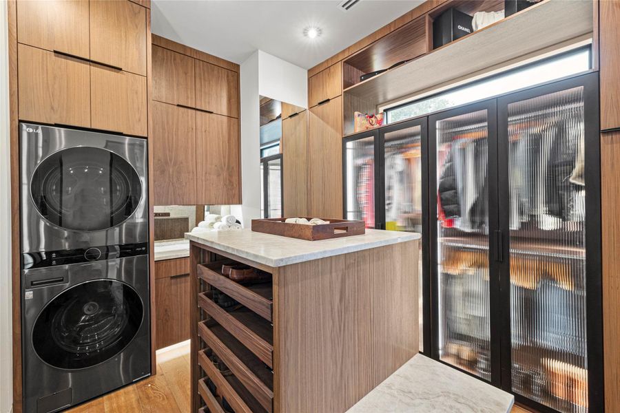 Custom closet system featuring wood-finish cabinetry and integrated laundry appliances
