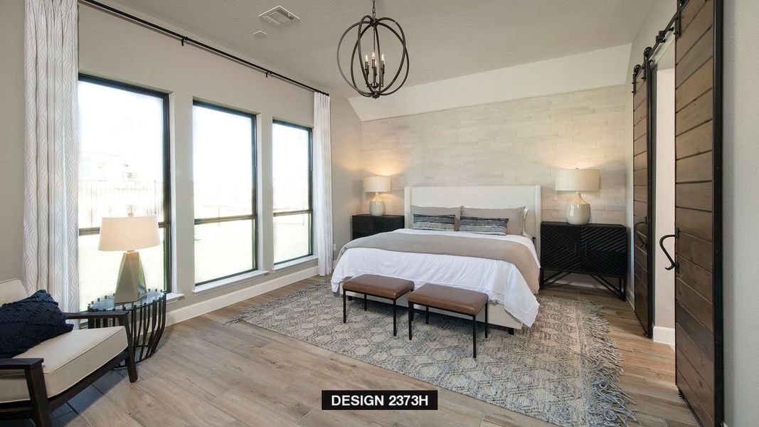 Bedroom with a barn door, light wood-type flooring, and a chandelier Bedroom with a barn door, light wood-type flooring, and a chandelier