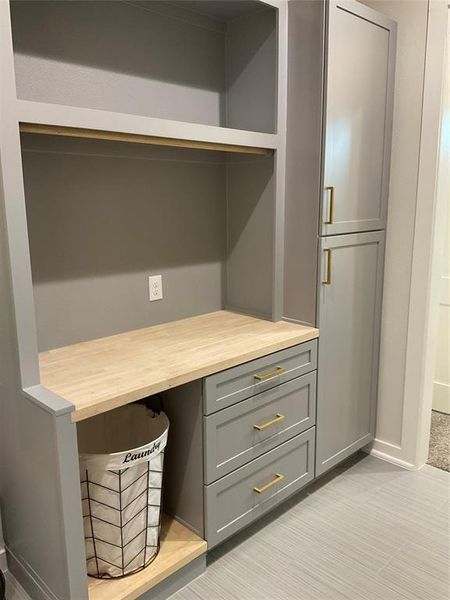 Custom built storage and folding area with butcher block counter top and custom painted cabinets in utility room