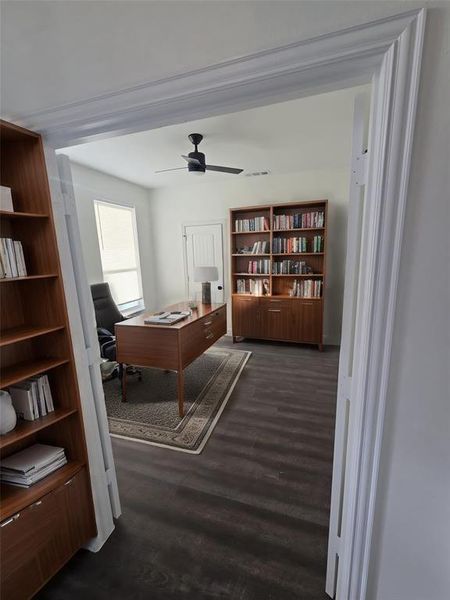 Office with dark hardwood / wood-style flooring, crown molding, and ceiling fan. All photos with staging are virtual and not included with the sale of the home.