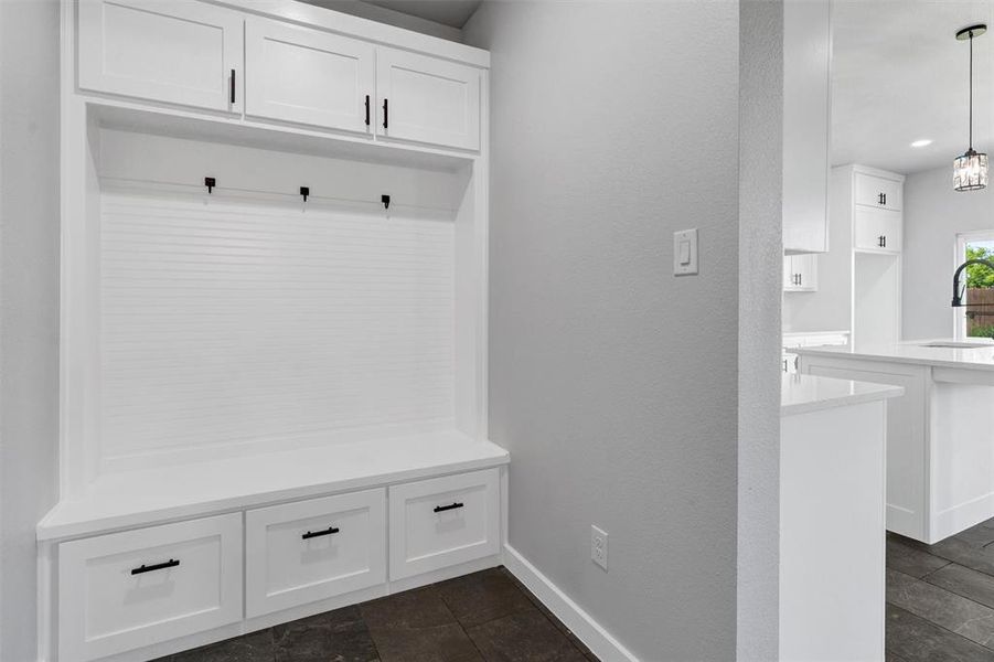 Mudroom with a sink, baseboards, and dark stone finish flooring
