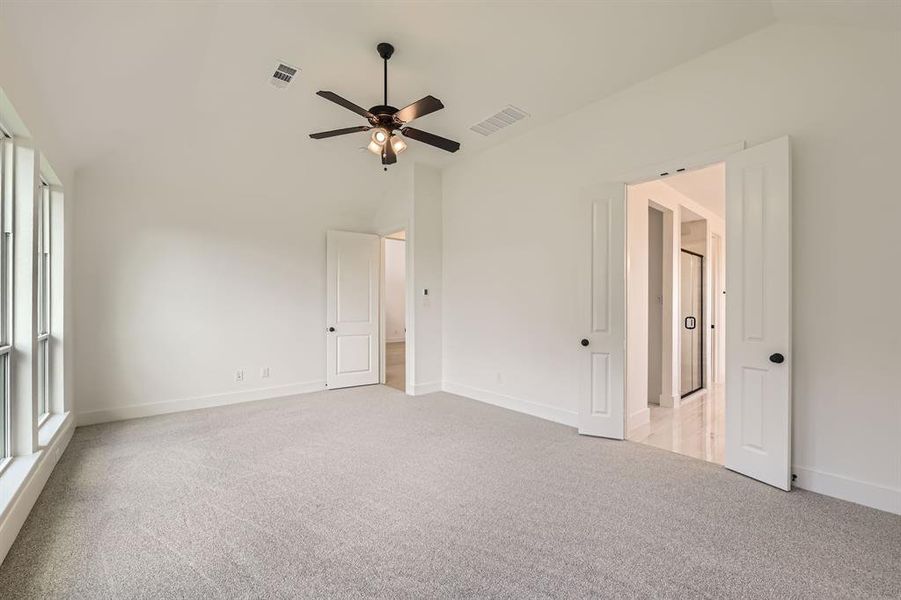 Unfurnished bedroom with vaulted ceiling, light colored carpet, and baseboards Unfurnished bedroom with vaulted ceiling, light colored carpet, and baseboards