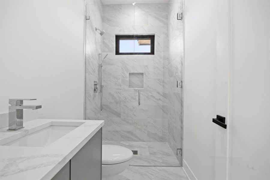 Full bath with a marble finish shower, marble finish floor, toilet, and vanity