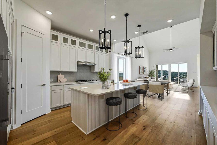 Kitchen featuring light countertops, white cabinetry, under cabinet range hood, light wood finished floors, and a high ceiling