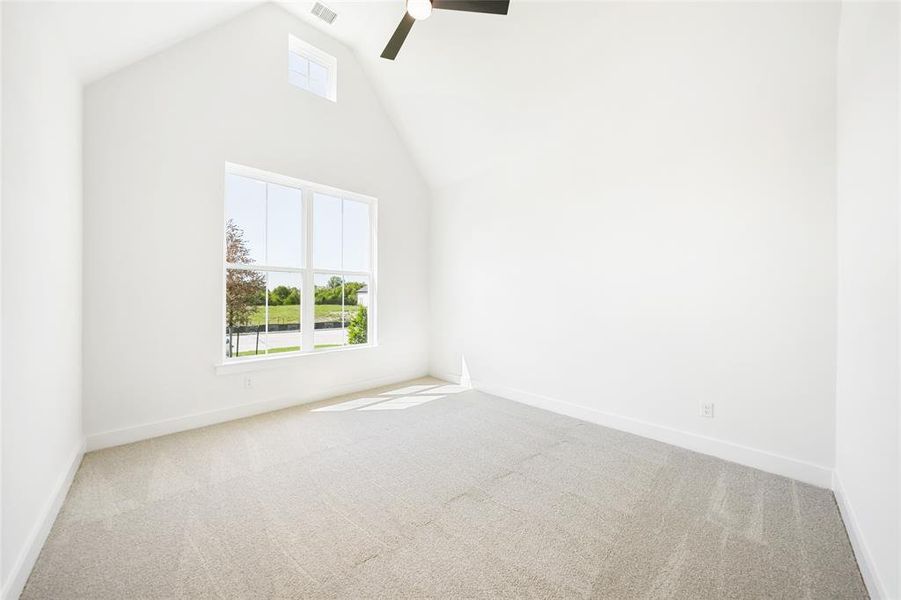 Empty room featuring high vaulted ceiling, light carpet, and a ceiling fan