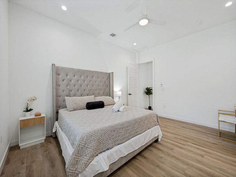 A tranquil bedroom with warm wood flooring features a contemporary tufted headboard and a discreetly integrated ceiling fan. A tranquil bedroom with warm wood flooring features a contemporary tufted headboard and a discreetly integrated ceiling fan.