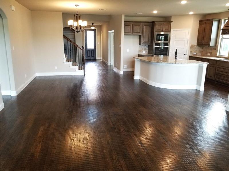 Enormous family room with wall of window, ceiling fan, and rich hardwood floors