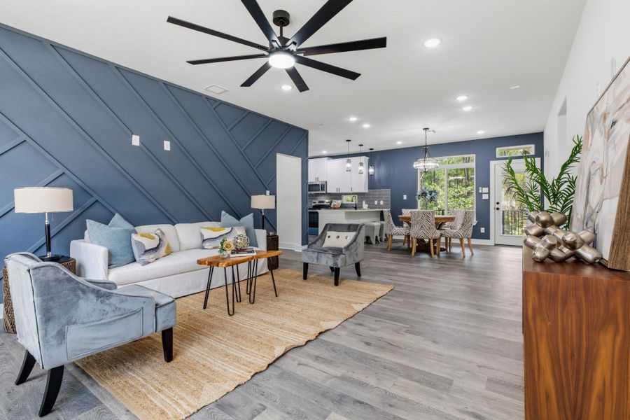 An open concept living and dining space showcases engineered hardwood flooring and modern lighting.