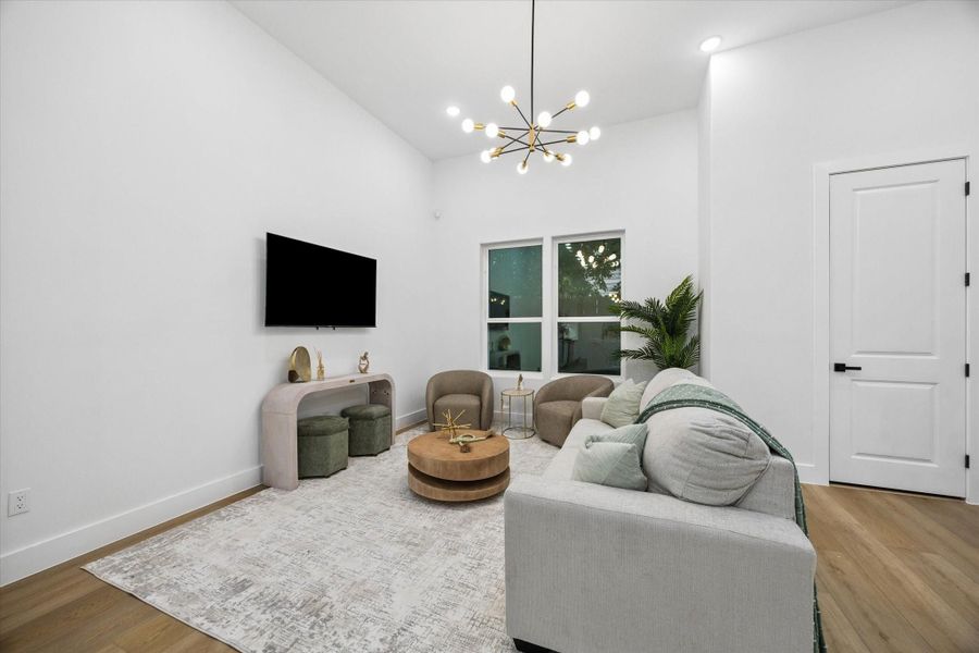 This modern living room features a high ceiling and neutral color palette. It includes a stylish chandelier, comfortable seating, and a wall-mounted TV. Large windows provide natural light, and the room is accented with contemporary furniture and decor, creating a cozy and inviting atmosphere. This modern living room features a high ceiling and neutral color palette. It includes a stylish chandelier, comfortable seating, and a wall-mounted TV. Large windows provide natural light, and the room is accented with contemporary furniture and decor, creating a cozy and inviting atmosphere.