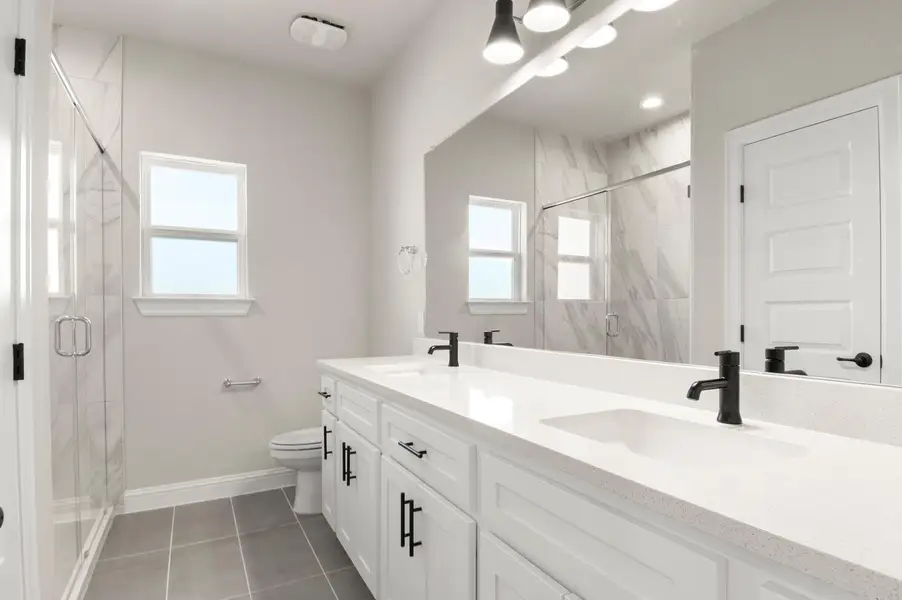 Full bathroom with double vanity, a marble finish shower, and light tile patterned floors Full bathroom with double vanity, a marble finish shower, and light tile patterned floors