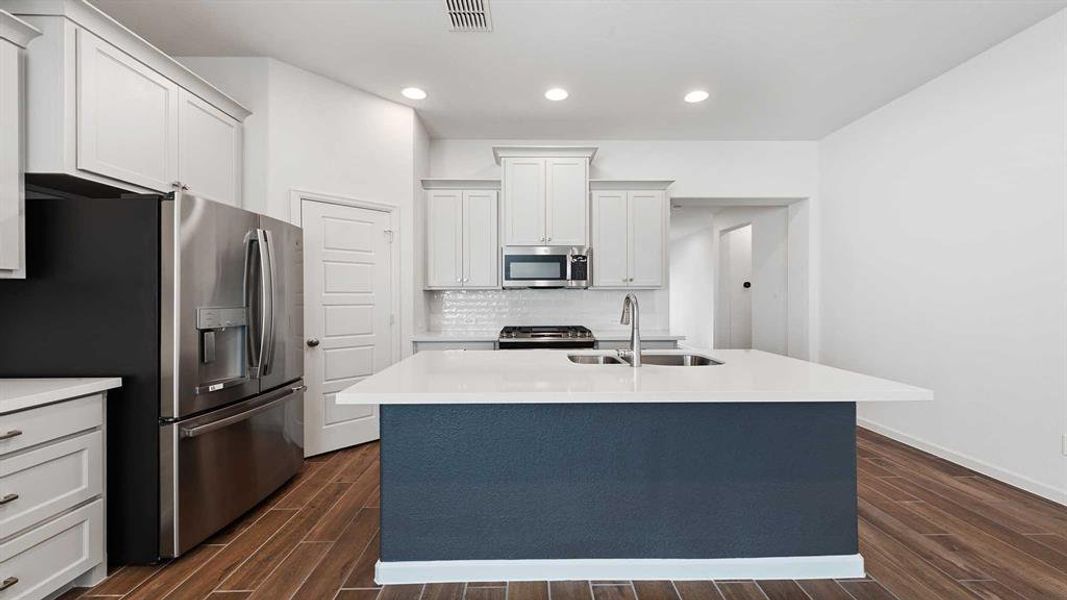 Kitchen featuring white cabinets, stainless steel appliances, a center island with sink, and sink