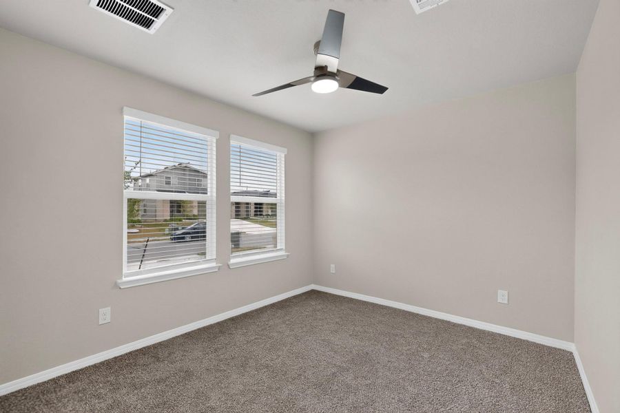 Double windows invite natural light across the soft carpeted floors of this versatile bedroom.