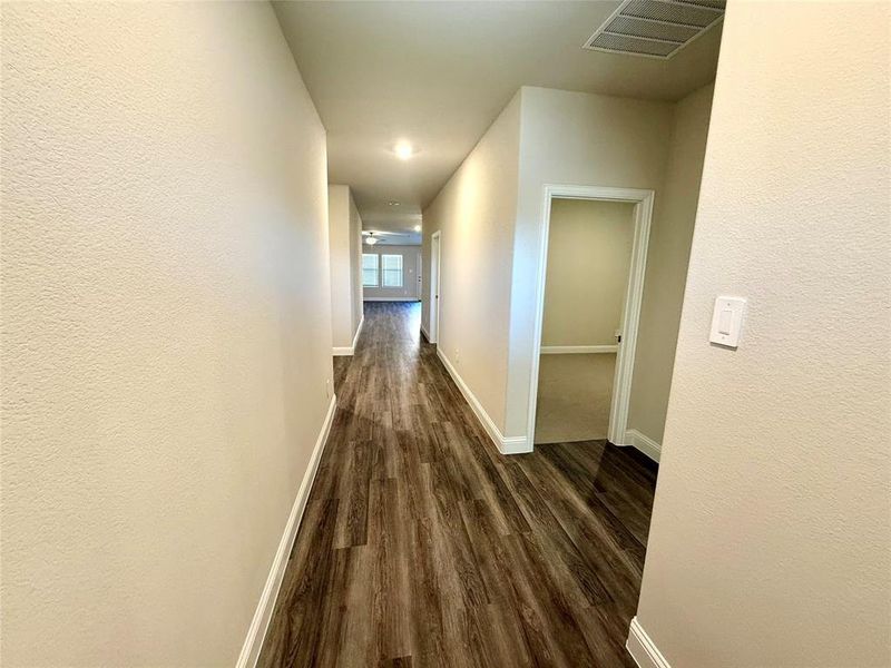 Long hallway featuring wood-finish flooring, recessed lighting, and neutral wall tones Long hallway featuring wood-finish flooring, recessed lighting, and neutral wall tones