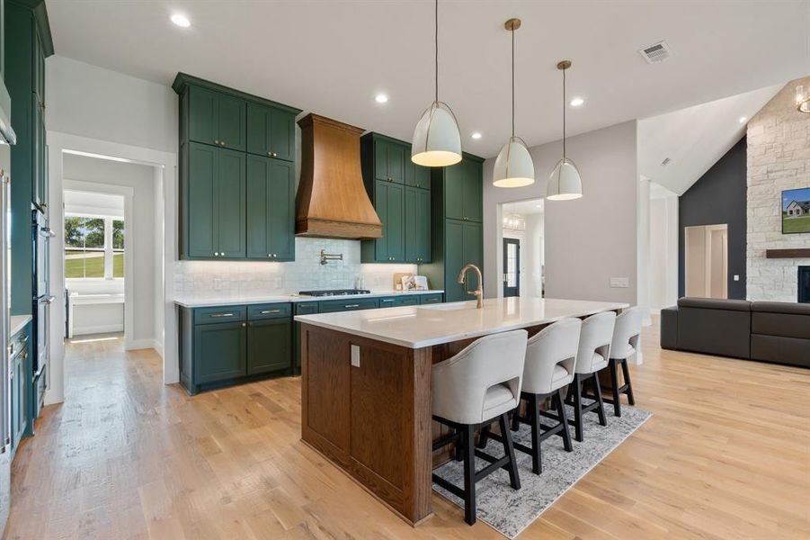 Kitchen featuring tasteful backsplash, gas cooktop, light wood-type flooring, and custom range hood