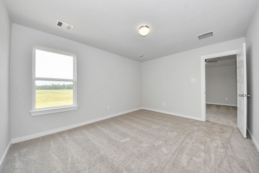 Secondary bedroom features plush carpeting, large windows that let in plenty of natural light, bright paint, and spacious closets. Sample photo of completed home with similar floor plan. Actual colors and selections may vary.