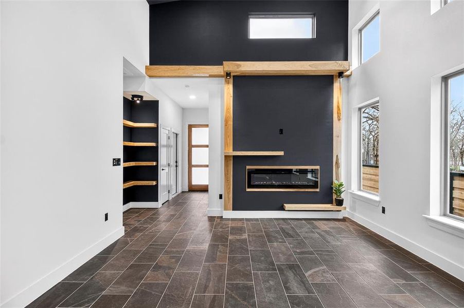 Unfurnished living room with a glass covered fireplace and a high ceiling Unfurnished living room with a glass covered fireplace and a high ceiling