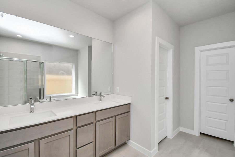 Escape to a spa-like oasis in this primary bathroom. Enjoy a walk-in shower with tile surround, a separate garden tub with custom detailing, and an elegant vanity featuring light countertops, modern hardware, and beautiful recessed lights. Experience luxury and relaxation in every detail. Sample photo of completed home with similar floor plan. Actual colors and selections may vary.