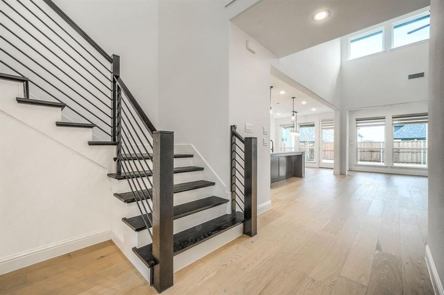 Stairs with visible vents, a high ceiling, baseboards, and wood finished floors