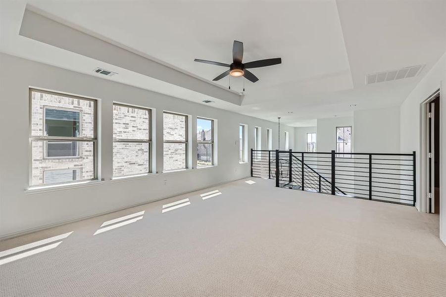 Carpeted spare room with ceiling fan and a raised ceiling