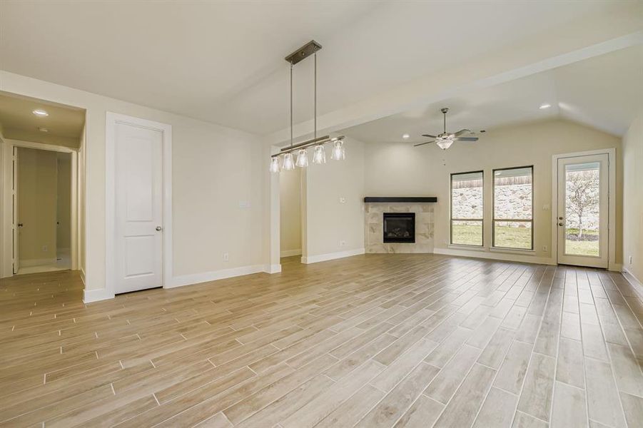 Unfurnished living room with recessed lighting, light wood finished floors, a premium fireplace, lofted ceiling, and ceiling fan