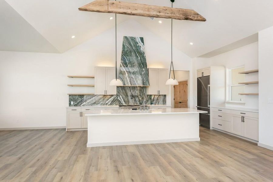 Kitchen with open shelves, decorative backsplash, pendant lighting, high quality fridge, and a kitchen island with sink Kitchen with open shelves, decorative backsplash, pendant lighting, high quality fridge, and a kitchen island with sink