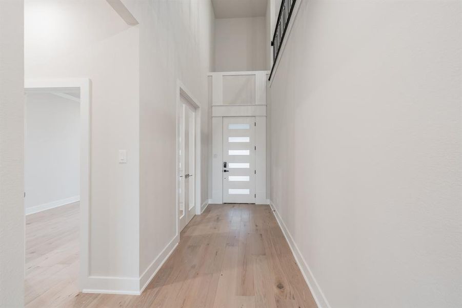 Corridor with a high ceiling and light wood-style flooring