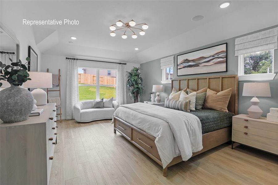 Spacious room featuring wood-finish flooring, a contemporary ceiling light fixture, recessed lighting, and a large window with privacy blinds Spacious room featuring wood-finish flooring, a contemporary ceiling light fixture, recessed lighting, and a large window with privacy blinds